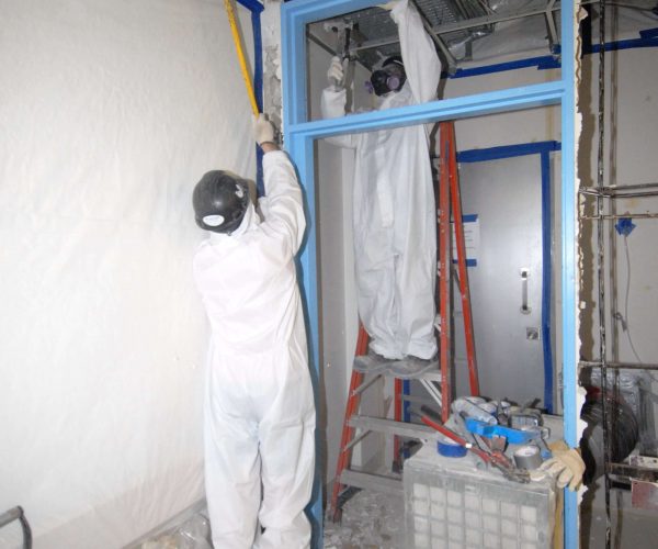Worker taking asbestos material off a wall